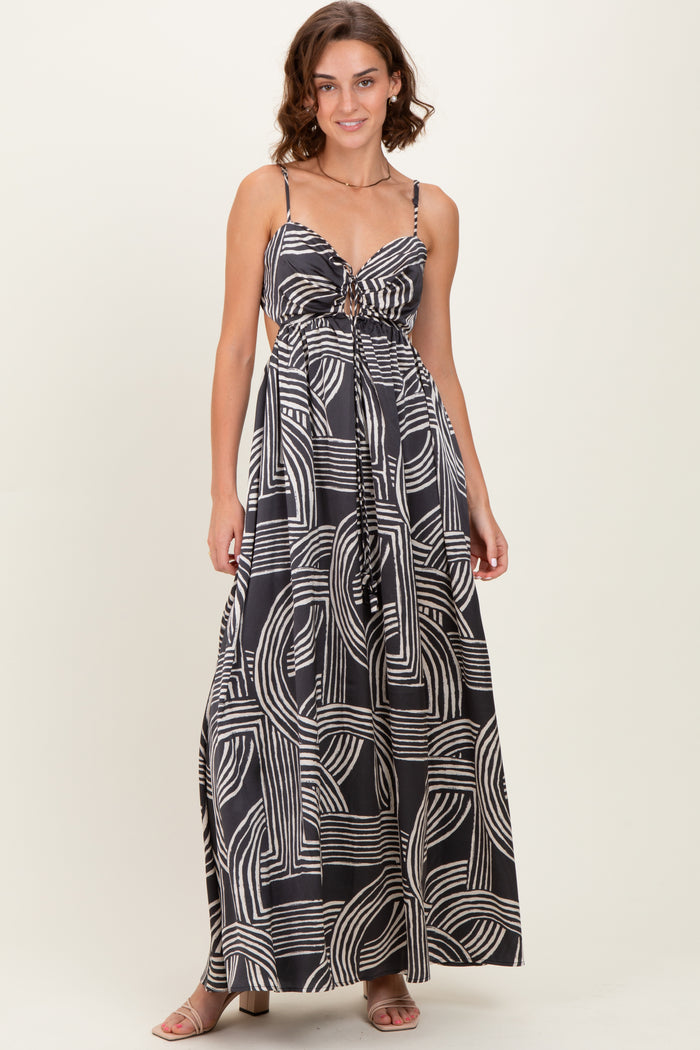 woman wearing a black and white patterned maxi dress with adjustable straps and a tie front detail