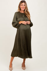woman wearing an olive green pleated maternity dress with a relaxed fit and a visible baby bump