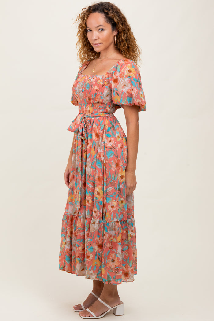 woman wearing a floral midi dress with puff sleeves and a cinched waist, standing against a neutral background
