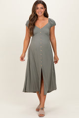 woman wearing a olive green maternity dress with short puff sleeves and button details, showing a baby bump