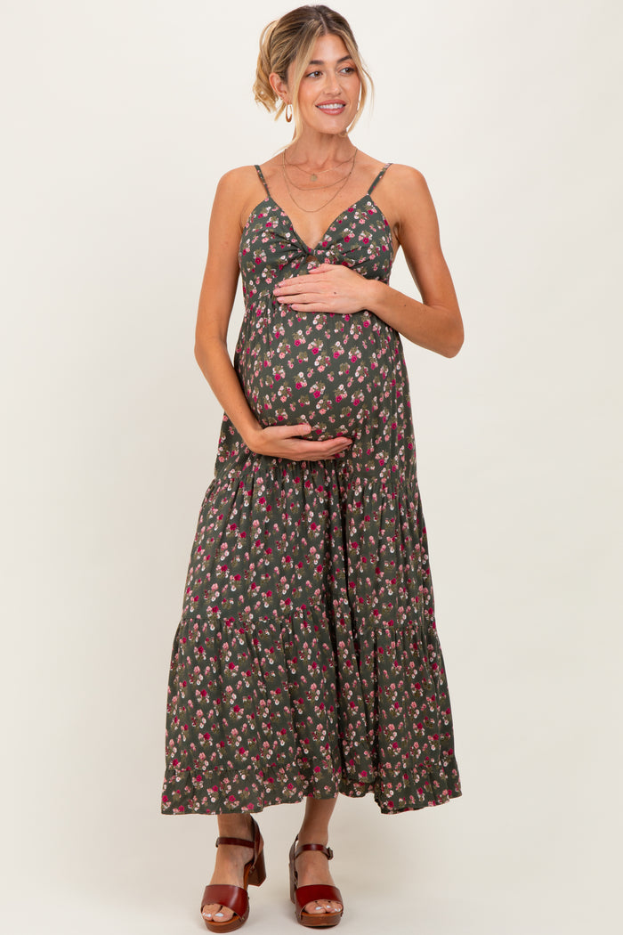 woman wearing a dark floral maternity maxi dress and holding her baby bump