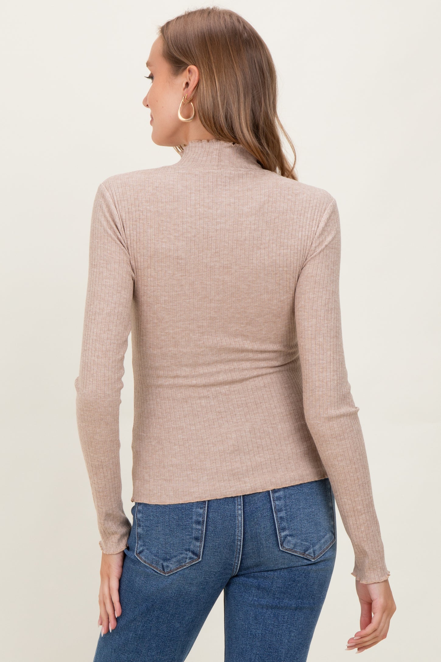 woman wearing a beige ribbed long sleeve maternity top, viewed from the back with jeans