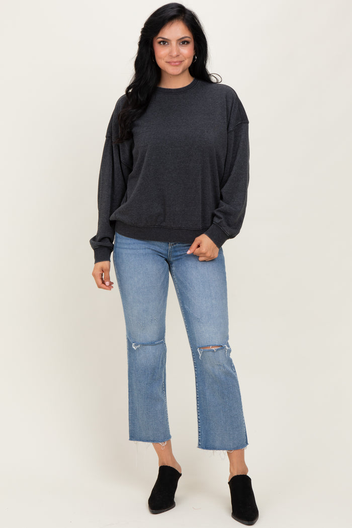 woman wearing a dark gray oversized sweatshirt with balloon sleeves and blue distressed cropped jeans