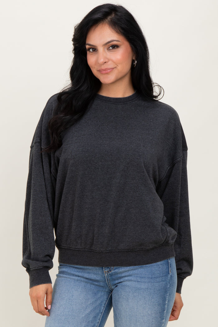 woman wearing a dark gray oversized sweatshirt with long sleeves and a relaxed fit, paired with light blue jeans