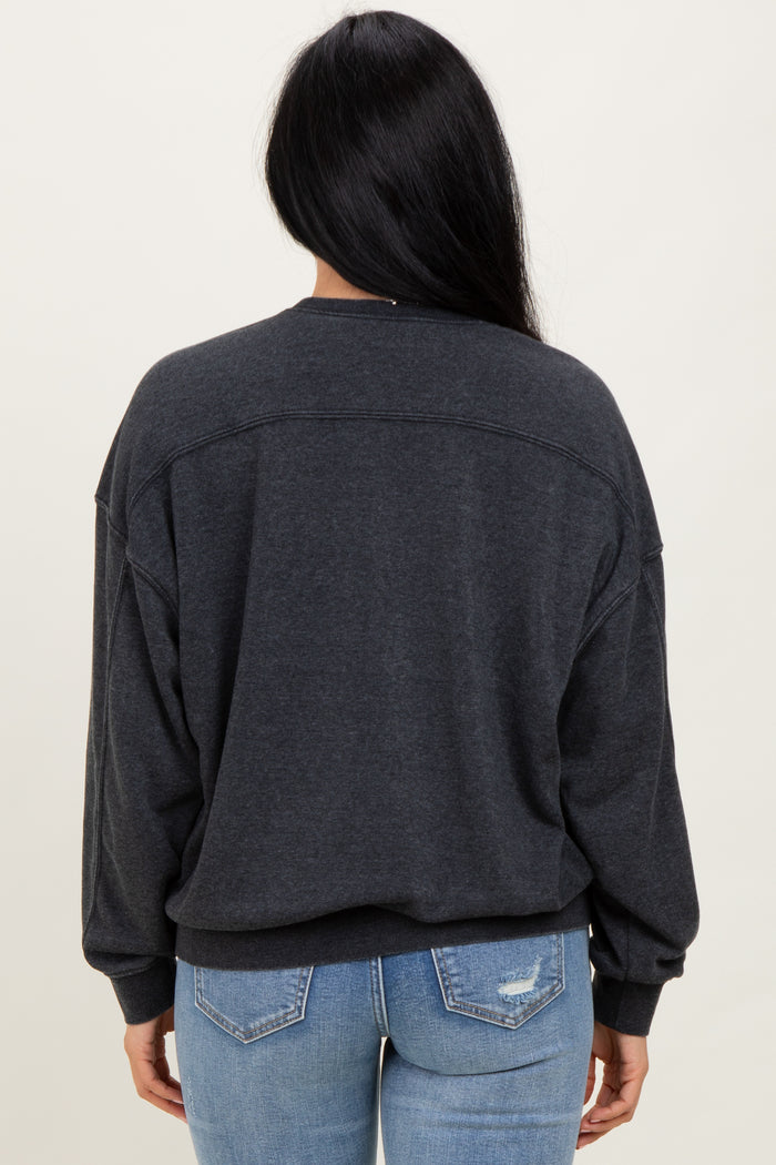 woman wearing a dark grey oversized sweatshirt with dropped shoulders and a relaxed fit paired with light blue jeans