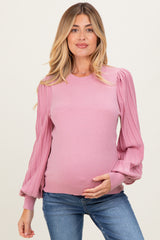 woman wearing a pink long sleeve maternity sweater with pleated sleeves and holding her baby bump