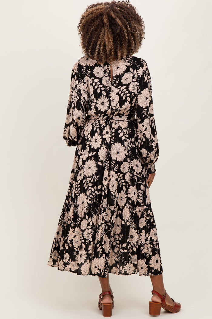 woman wearing a black floral maternity dress with long sleeves and tiered hem viewed from the back