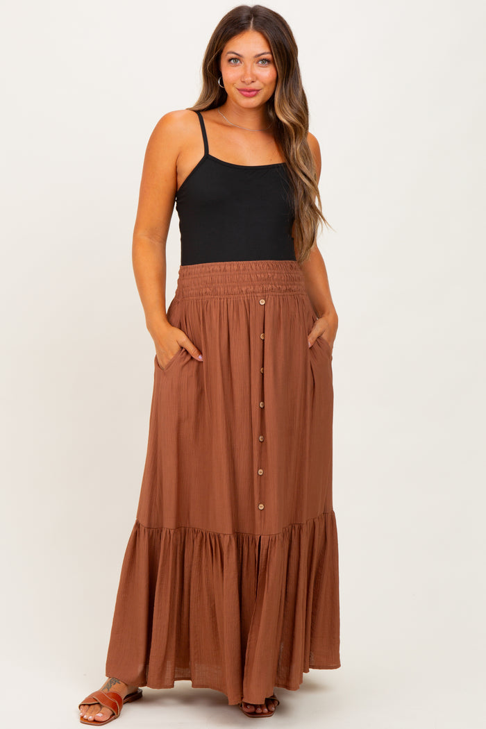 woman wearing a black tank top and a brown maternity maxi skirt with buttons and pockets, displaying a baby bump