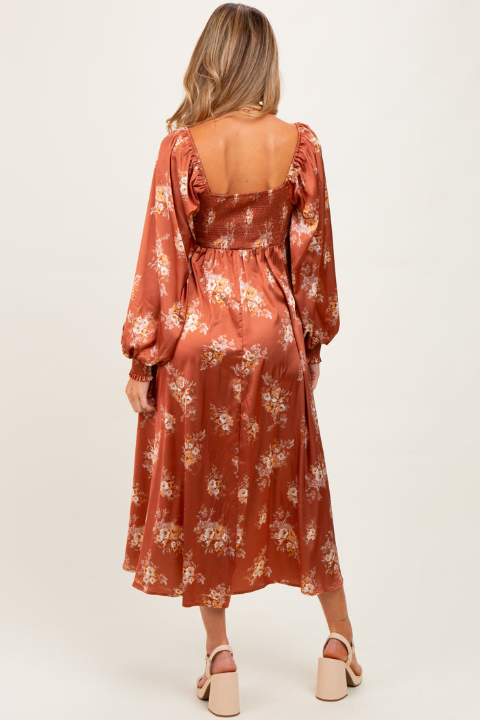 woman wearing a rust floral maternity maxi dress with puff sleeves and a smocked bodice, showing a baby bump