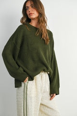 woman wearing a dark green oversized waffle knit sweater with long sleeves and relaxed fit pants