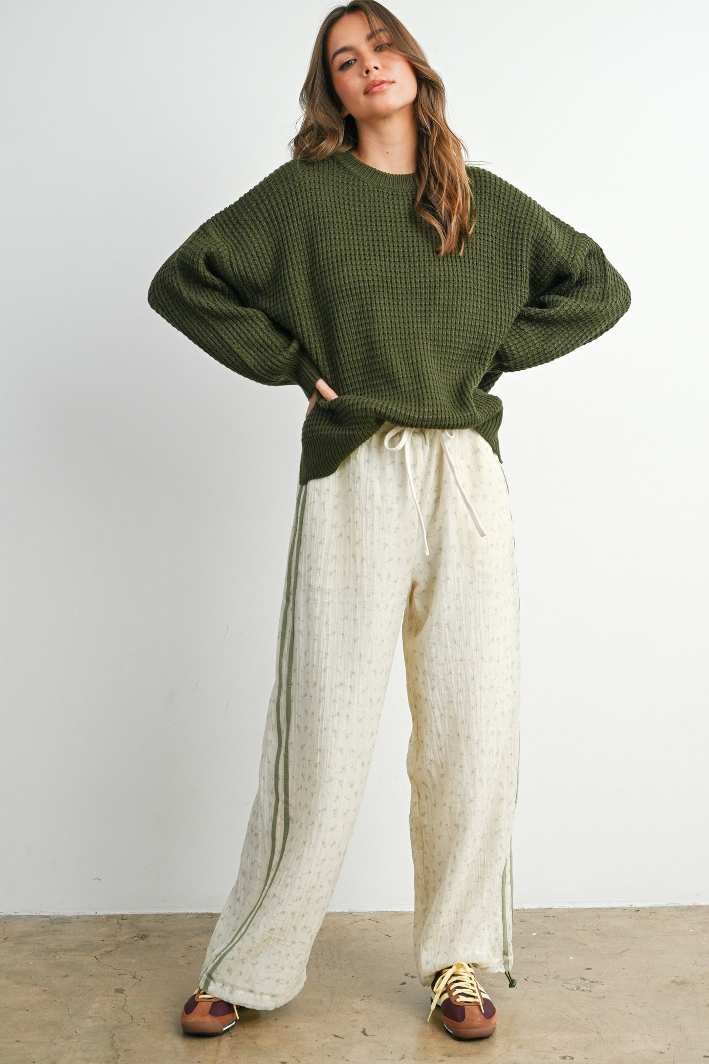 woman wearing an olive green oversized sweater and cream colored textured wide-leg pants