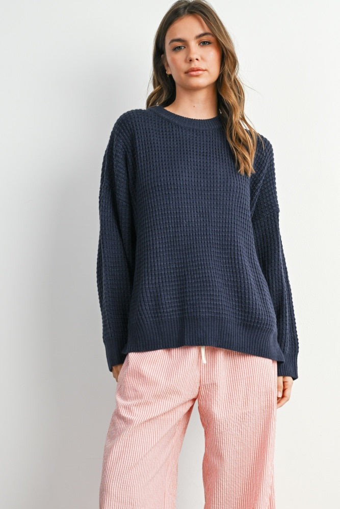 woman wearing a navy blue waffle knit oversized sweater and pink striped wide-leg pants