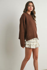 woman wearing a brown knitted sweater paired with a white ruffled mini skirt