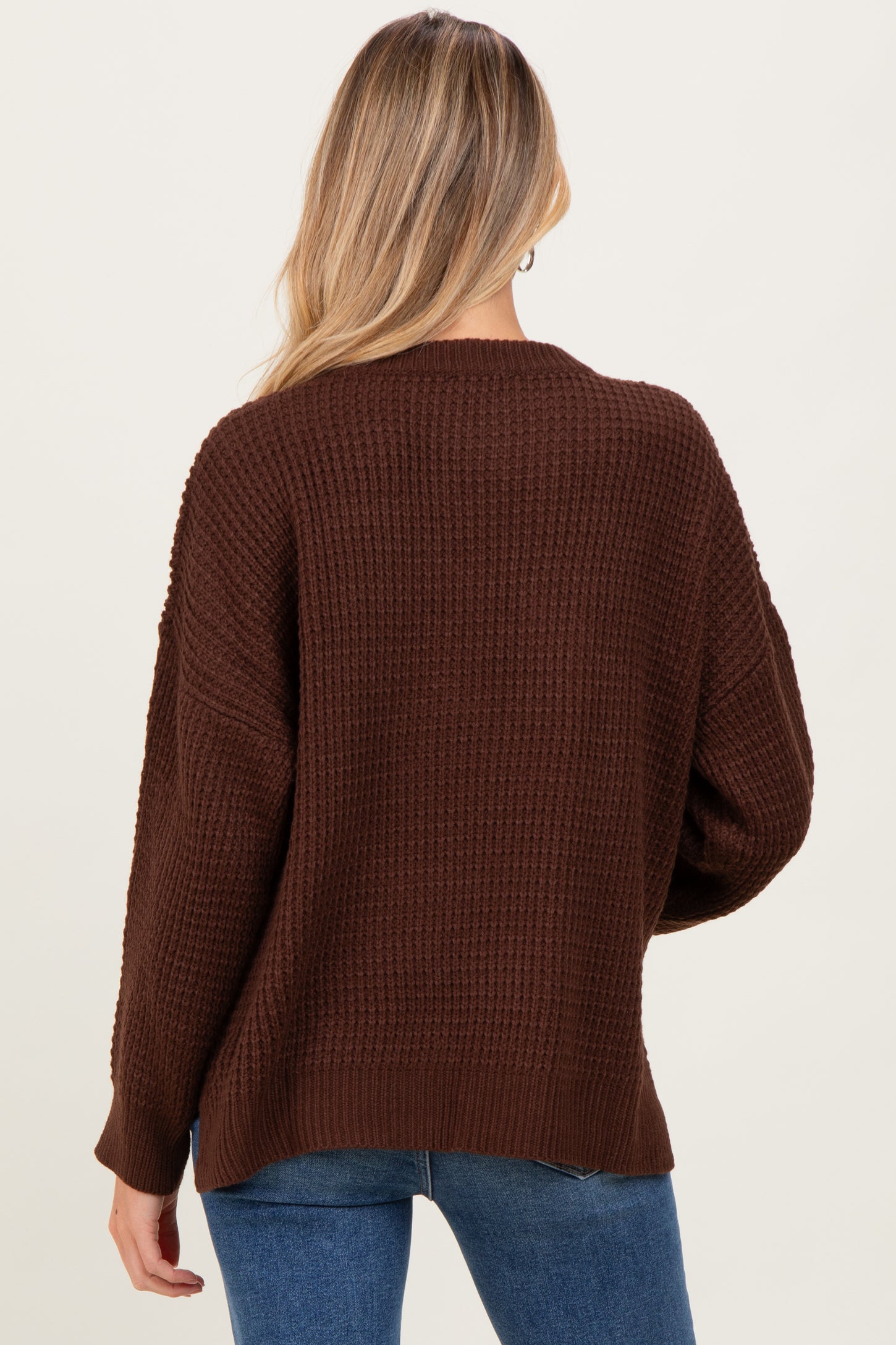 woman wearing a brown knitted maternity sweater with a loose fit and long sleeves, seen from the back