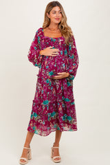 woman wearing a purple floral maternity dress with a tiered design and holding her baby bump