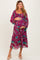 woman wearing a purple floral maternity dress with a tiered design and holding her baby bump