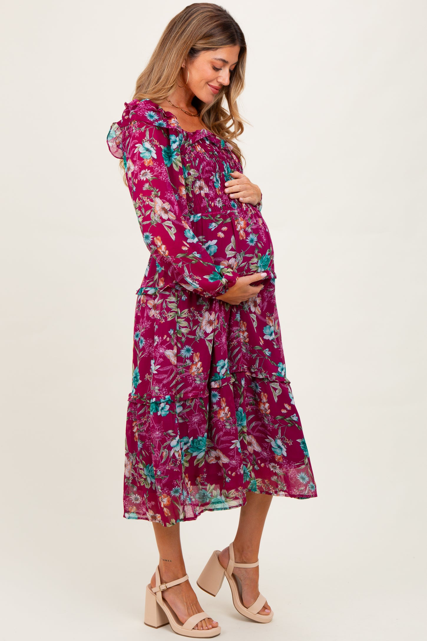 woman wearing a berry floral print maternity dress and holding her baby bump