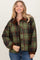 woman wearing a green and brown plaid jacket with a collar, smiling while posing for the photo