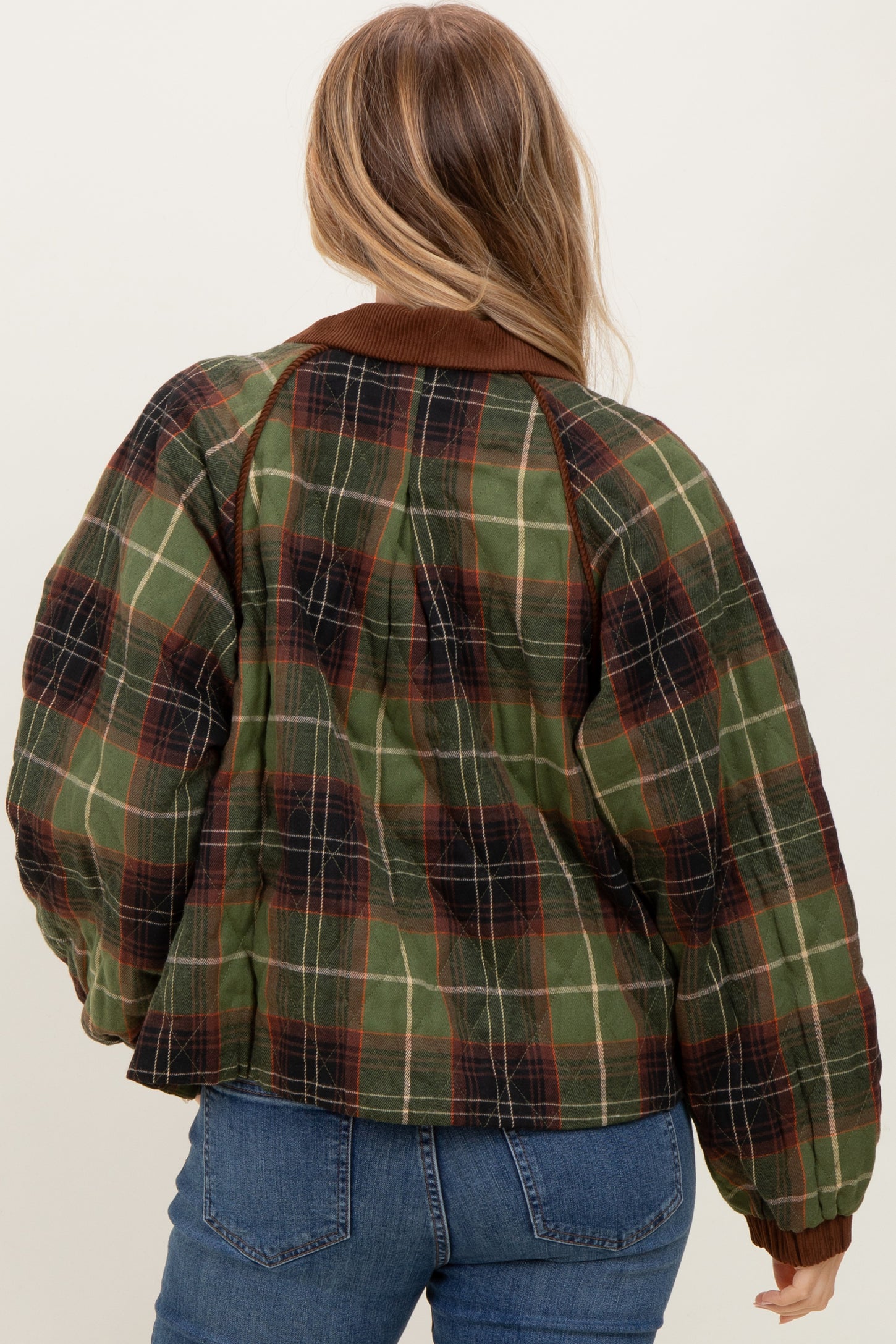 woman wearing a green and brown plaid oversized jacket with a brown collar and back view visible