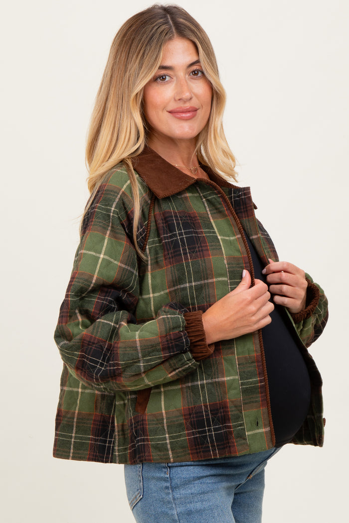 woman wearing a green and brown plaid maternity jacket with a brown collar and elastic cuffs, and showcasing her baby bump