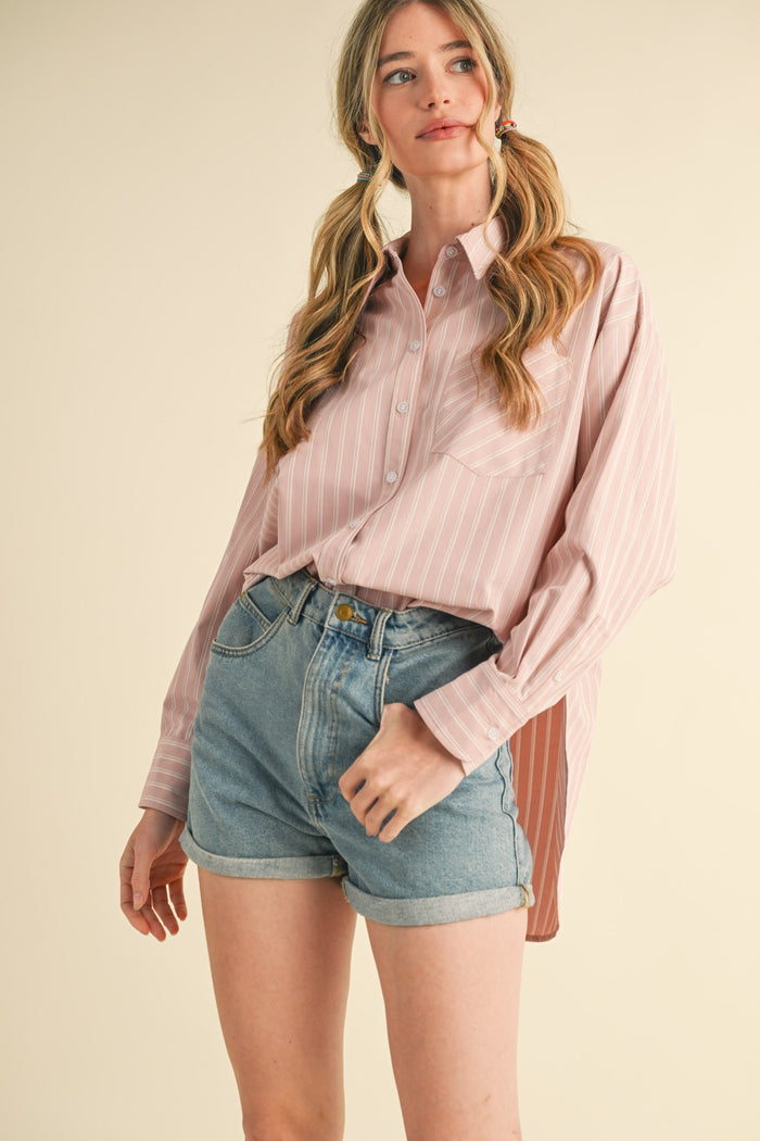 woman wearing a light pink striped button-up shirt and high-waisted denim shorts