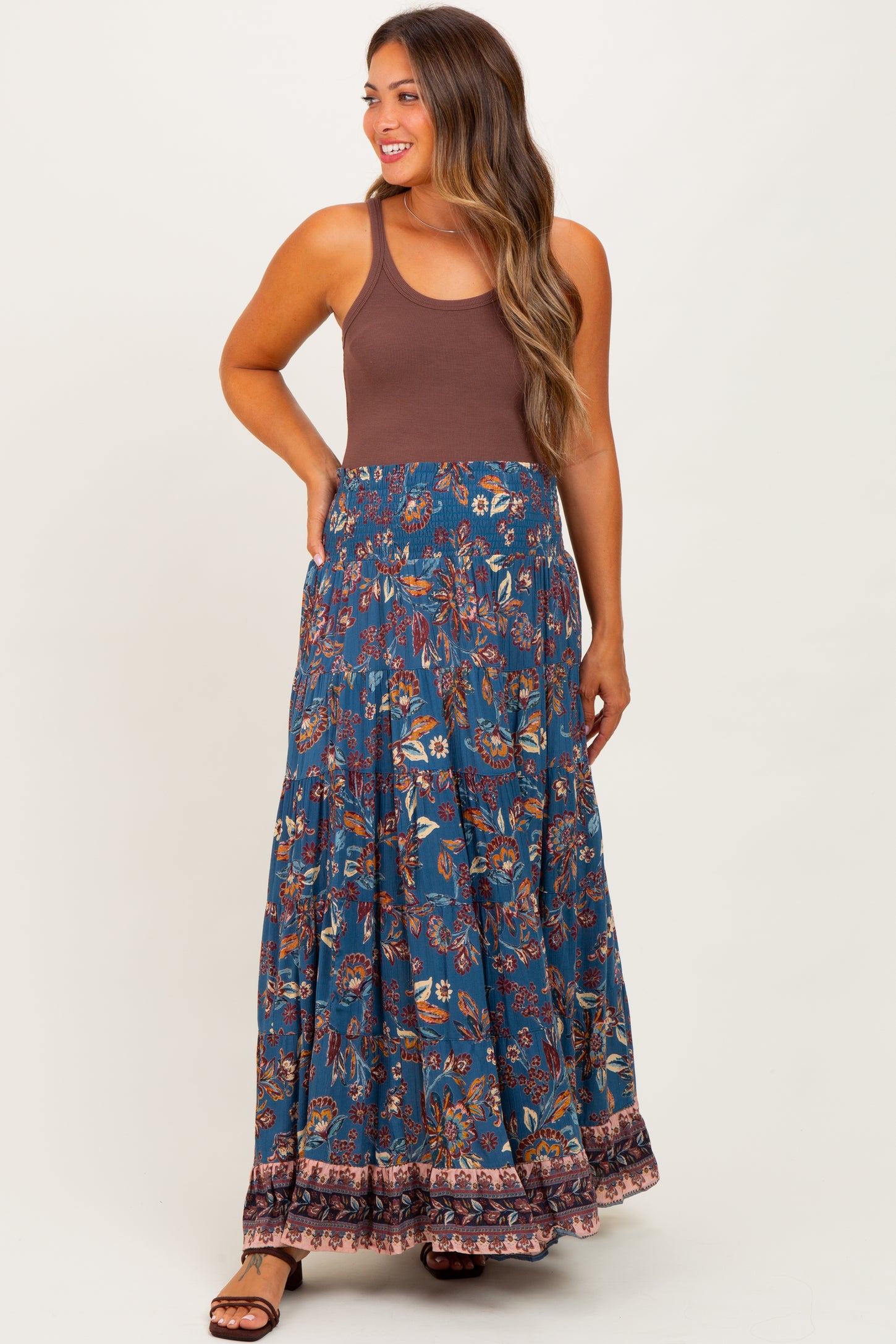 woman wearing a brown tank top and a floral print navy blue maternity maxi skirt with a tiered design
