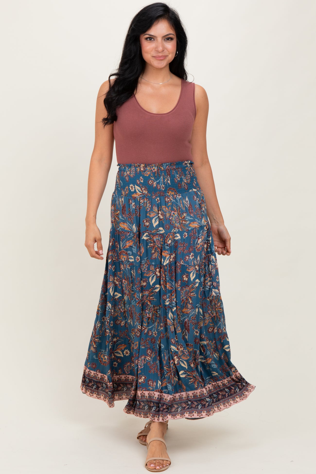 woman wearing a maroon tank top and a flowy blue floral maxi skirt with a ruffled hem