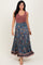 woman wearing a maroon tank top and a flowy blue floral maxi skirt with a ruffled hem