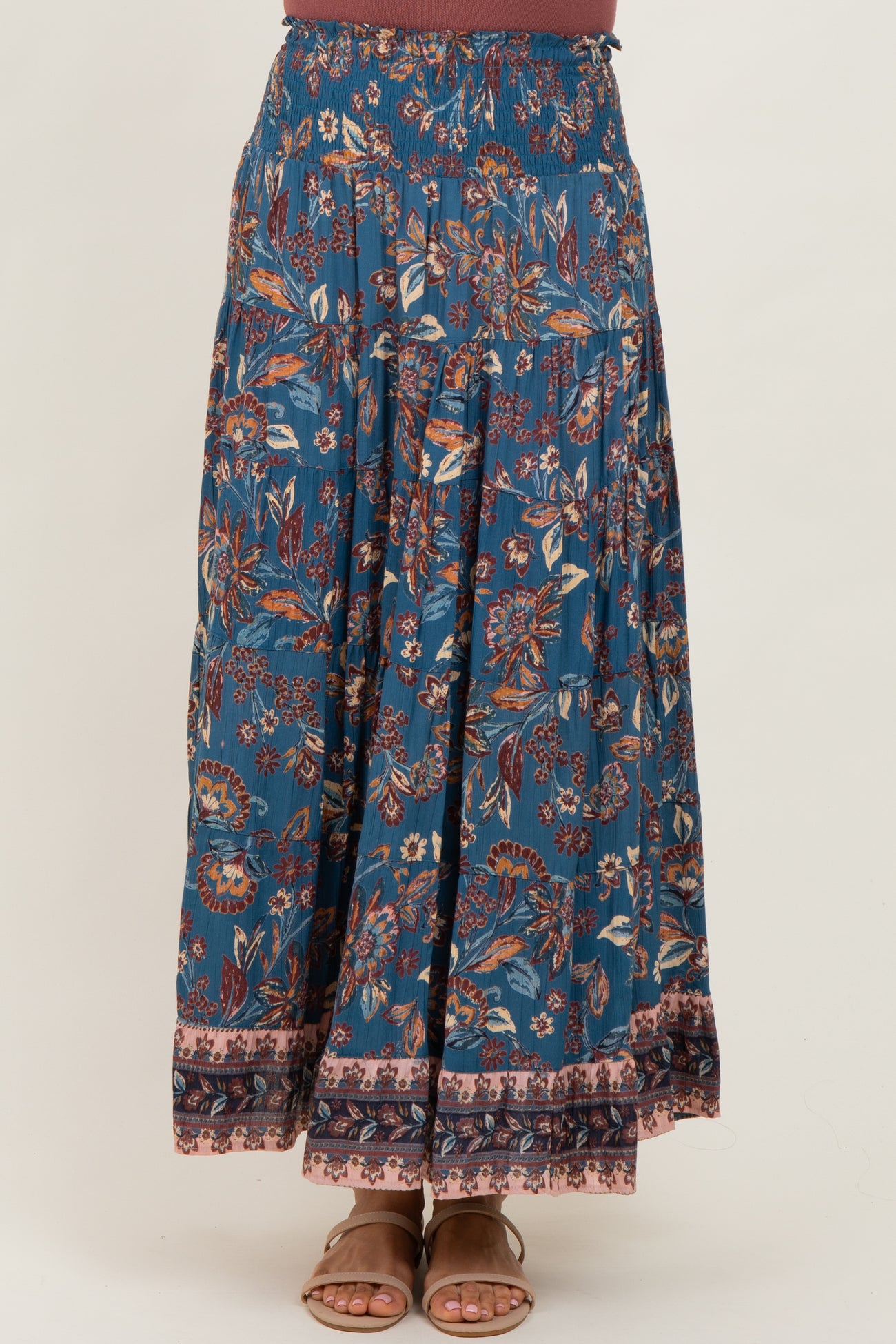 woman wearing a long flowy blue bohemian maxi skirt with floral patterns and a wide waistband