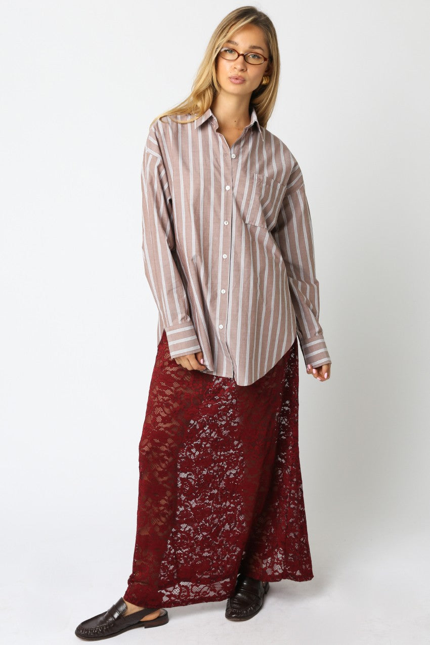 woman wearing a striped brown long sleeve button-up shirt and a burgundy lace maxi skirt