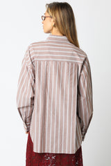 woman wearing a brown and white striped oversized button-up shirt with long sleeves, viewed from the back