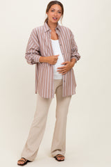 woman wearing a light brown and white striped maternity button-up shirt and beige pants, showing her baby bump