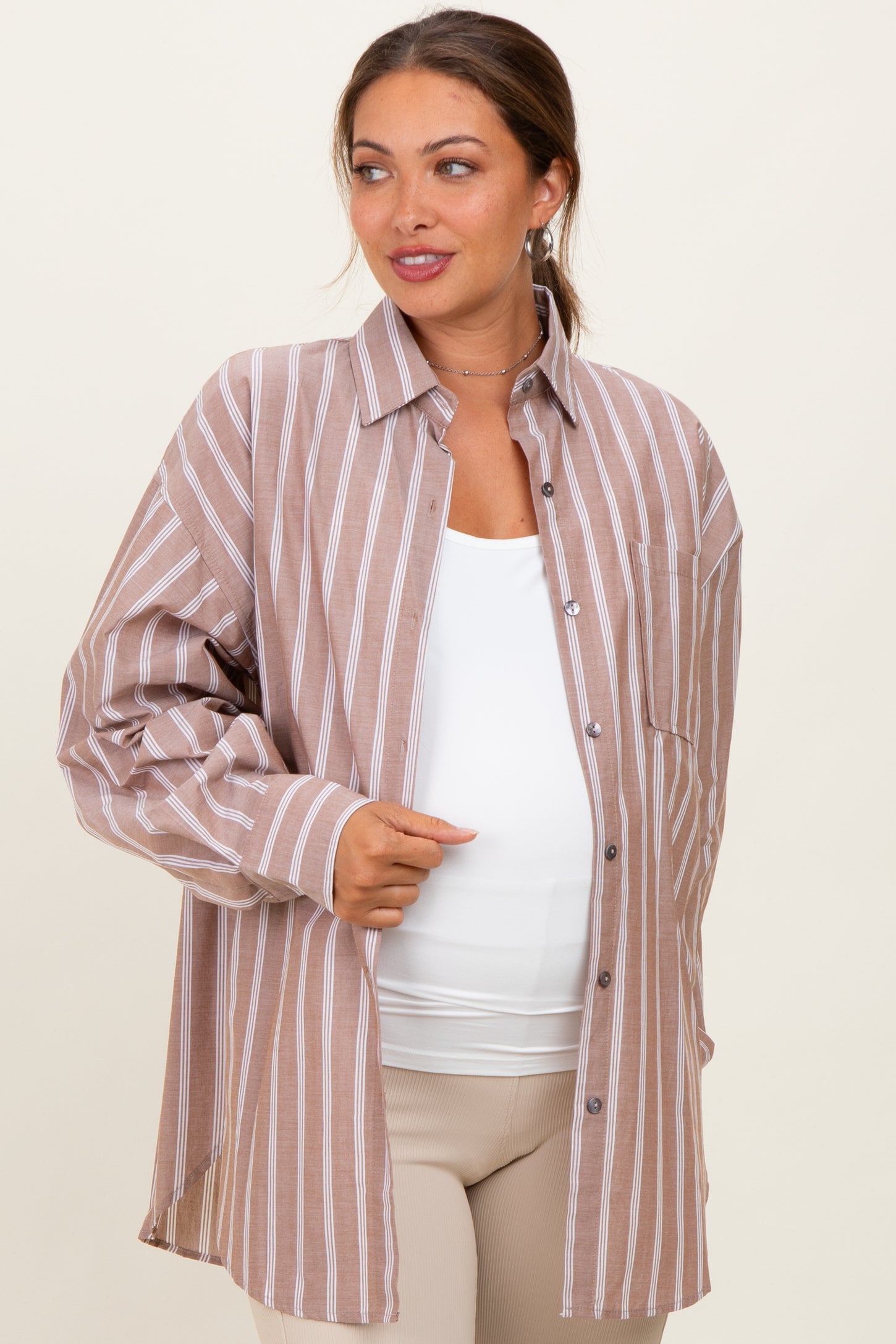 woman wearing a brown striped maternity button-up shirt with a white tank underneath and a visible baby bump