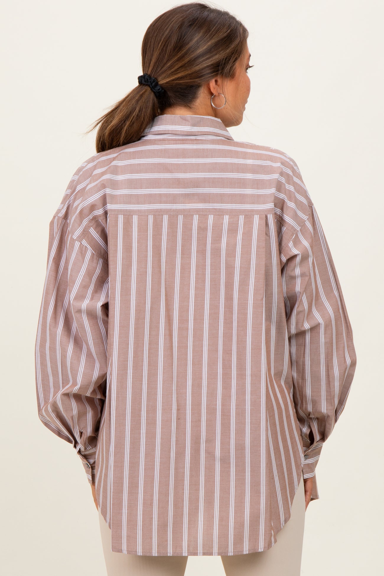 woman wearing a striped maternity shirt with oversized sleeves and a relaxed fit, showing the back view