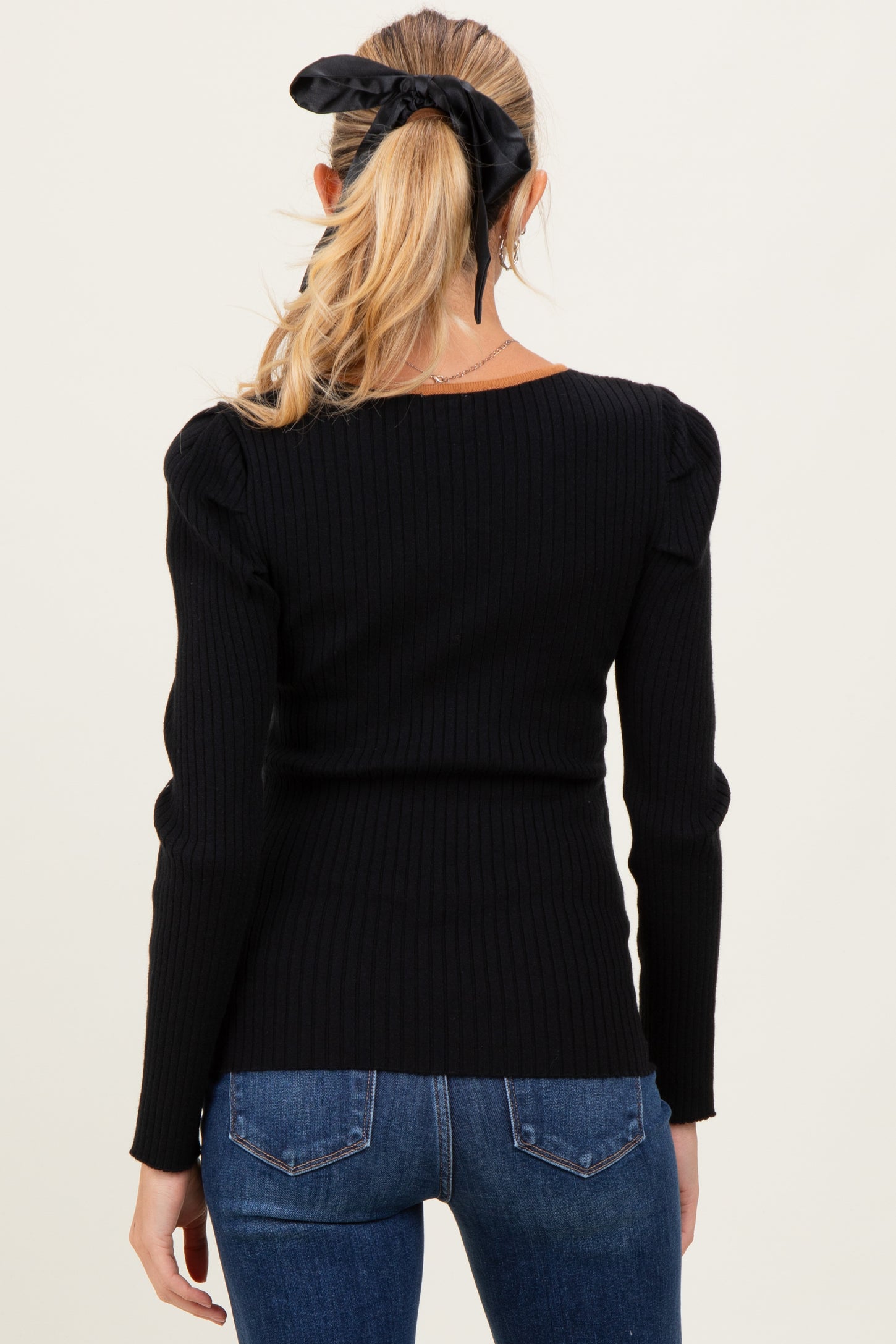 woman wearing a black ribbed maternity top with puff sleeves, seen from the back