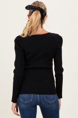 woman wearing a black ribbed maternity top with puff sleeves, seen from the back