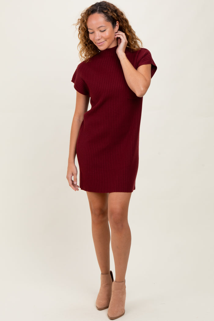 woman wearing a burgundy ribbed knit short sleeve dress with a high neckline and tan ankle boots