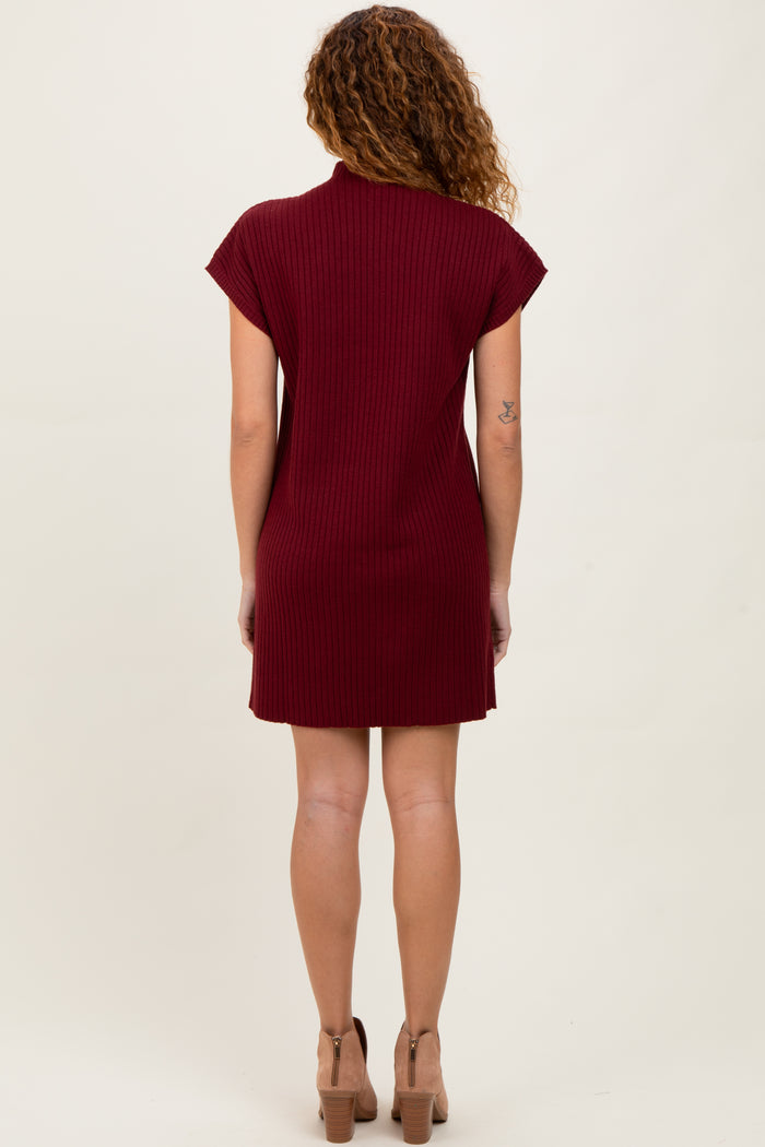 woman wearing a burgundy ribbed short sleeve dress, styled with a high neckline and a fitted silhouette