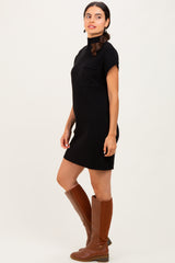 woman wearing a black ribbed short sleeve dress with a chest pocket and knee-high brown leather boots