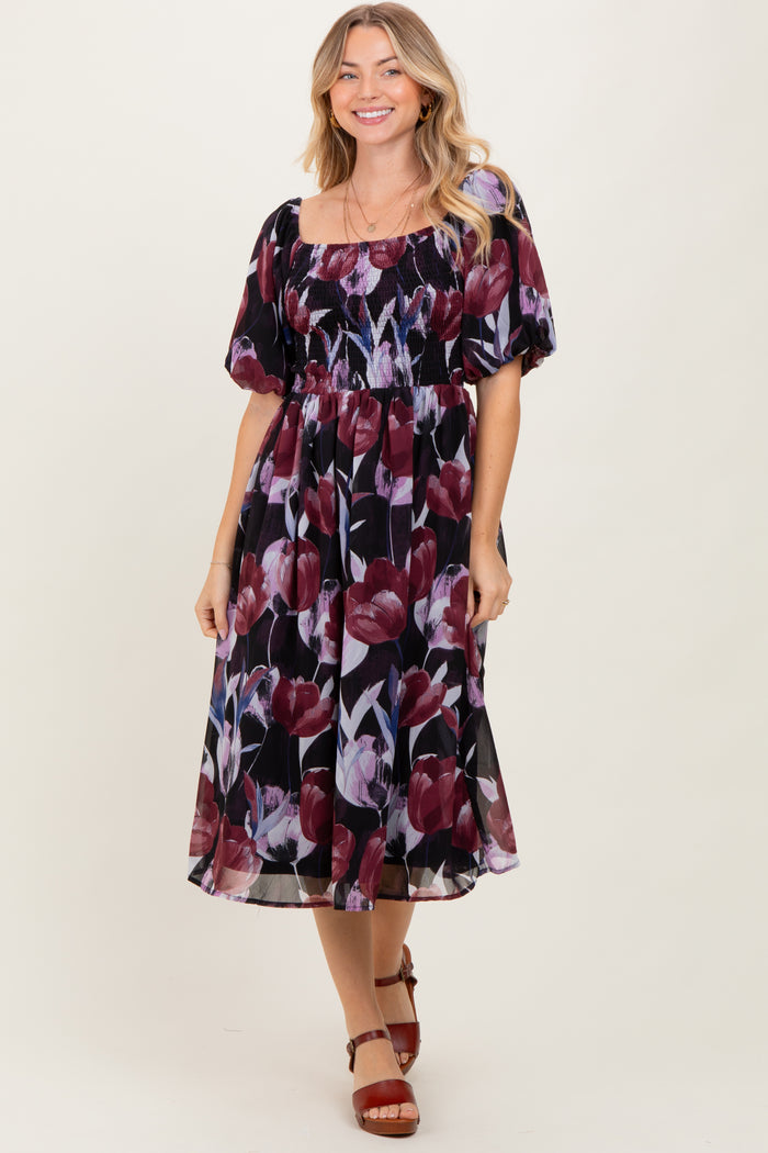 woman wearing a black floral midi dress with puff sleeves and a square neckline