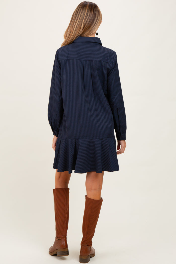 woman wearing a navy striped maternity dress with a ruffled hem and long sleeves, showing the back view