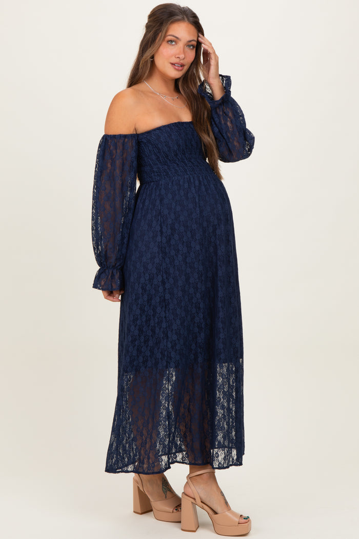 woman wearing a navy blue off-the-shoulder lace maternity dress with puff sleeves and a visible baby bump
