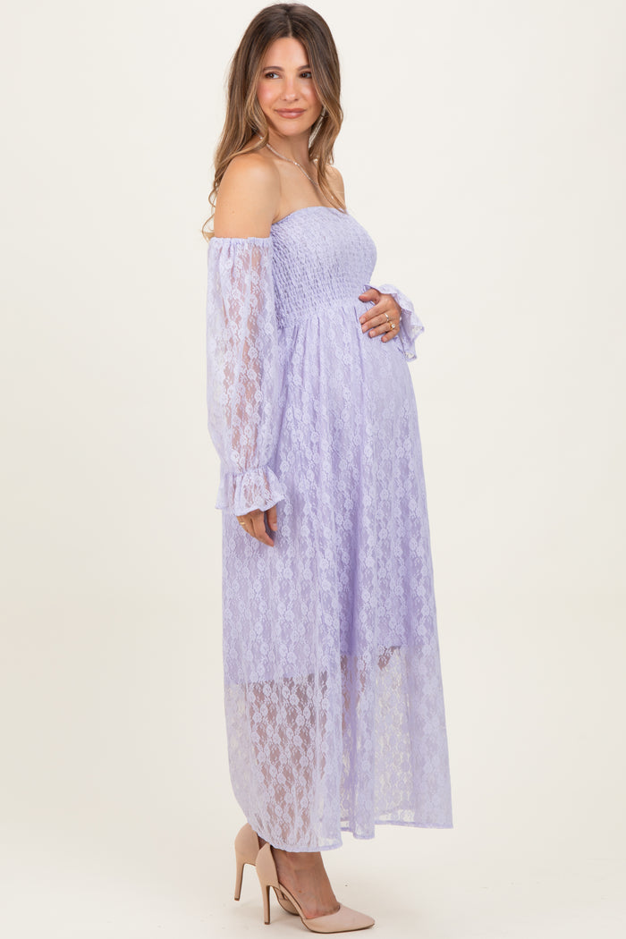 woman wearing a lavender off-shoulder lace maternity dress with long sleeves and holding her baby bump