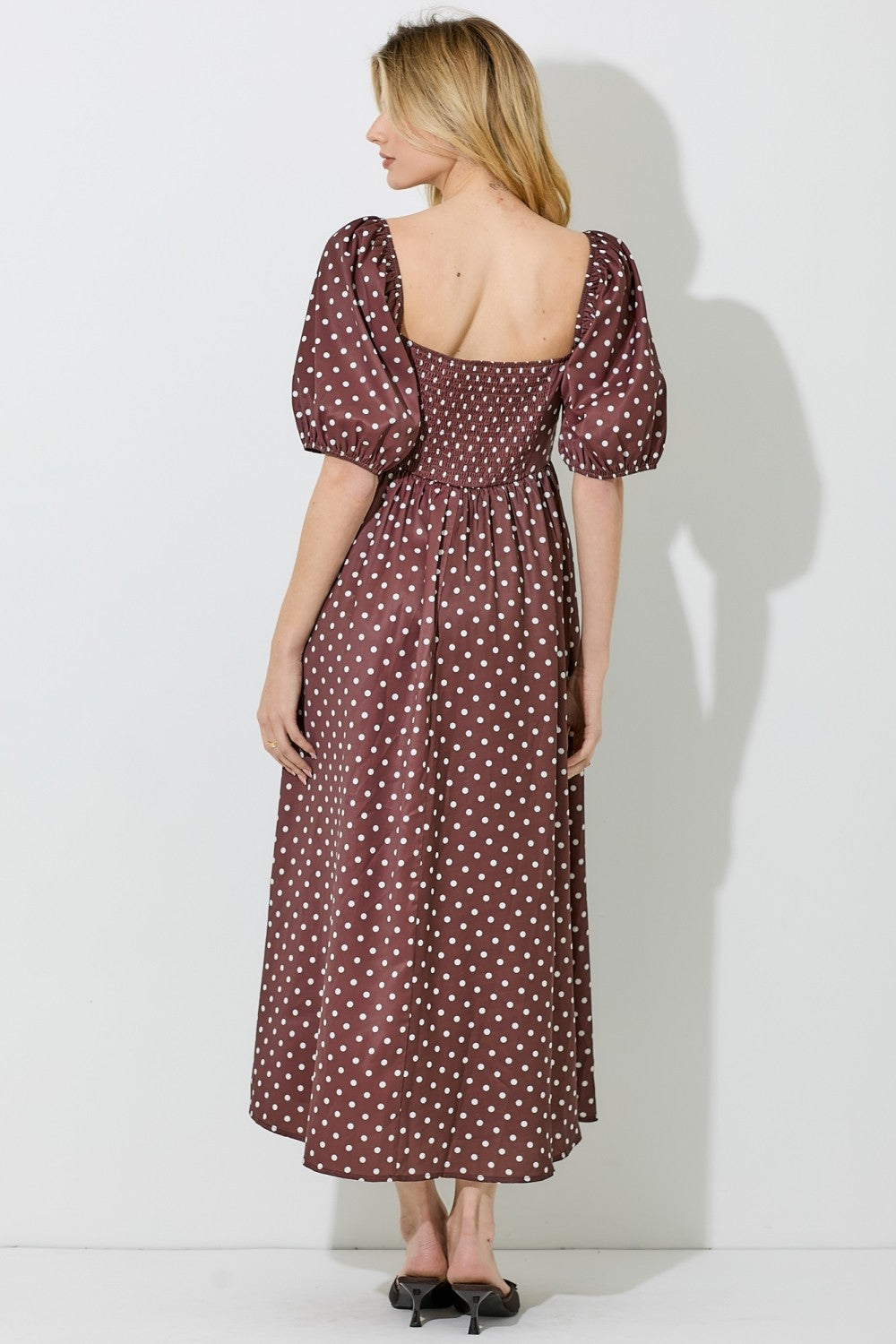 woman wearing a brown polka dot midi dress with puff sleeves and a smocked back view