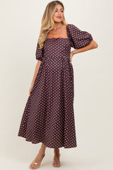 woman wearing a brown polka dot maternity dress with puff sleeves and a flowy skirt, showcasing her baby bump