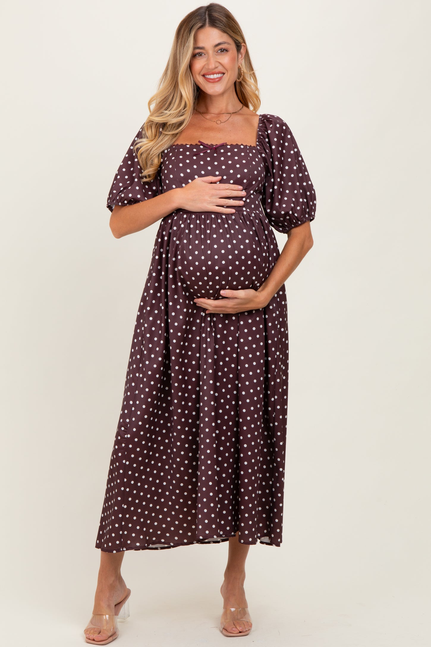 woman wearing a brown polka dot maternity dress with puff sleeves and a baby bump visible