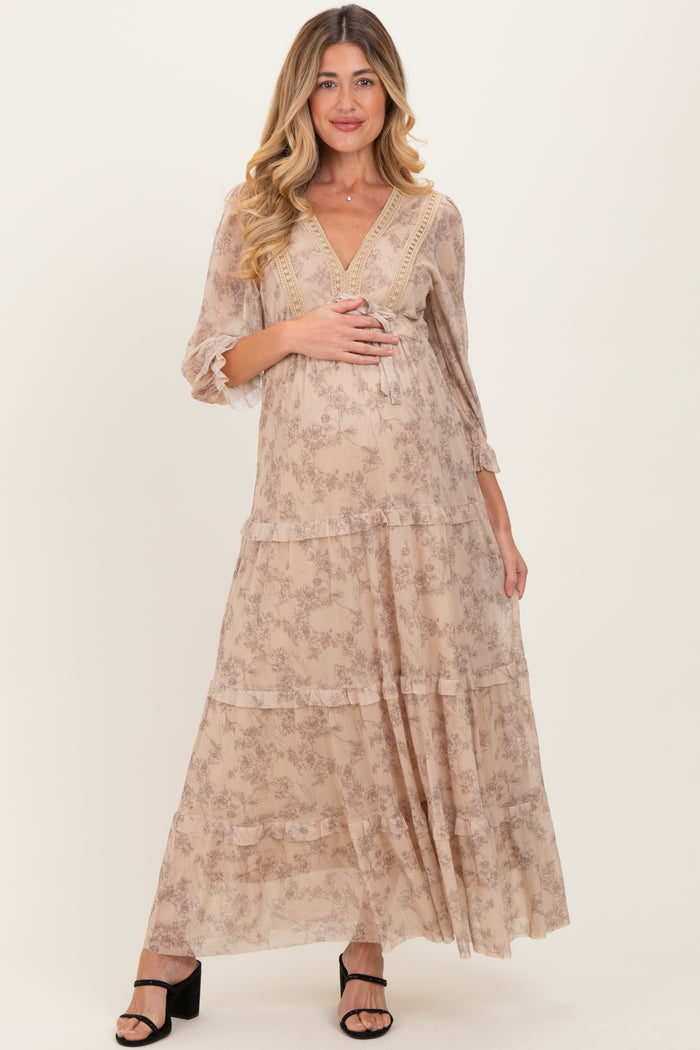 woman wearing a flowy beige floral maternity maxi dress with three-quarter sleeves and a visible baby bump