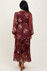 woman wearing a burgundy floral maxi dress with long sleeves and a tiered skirt, shown from the back