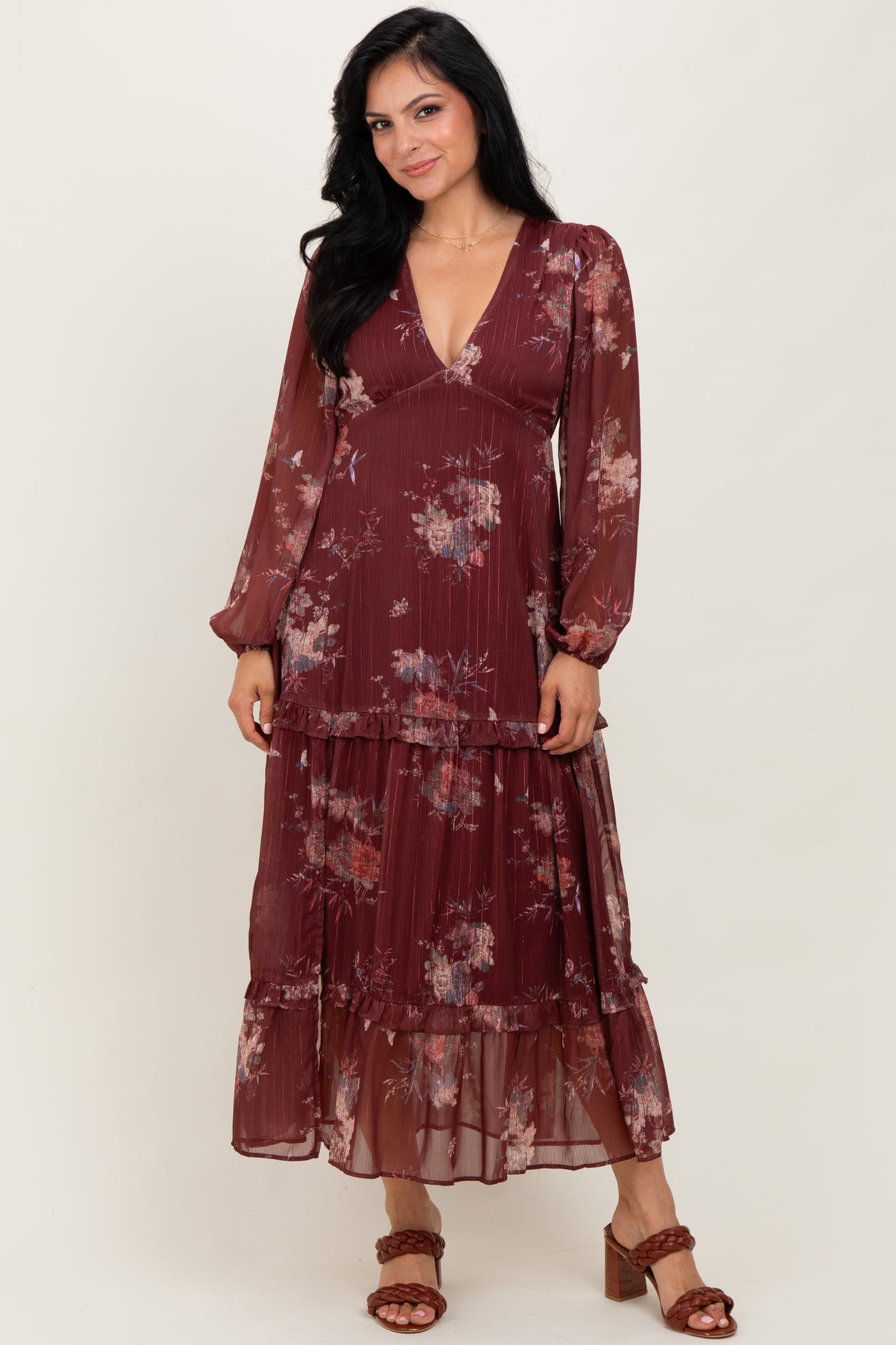 woman wearing a burgundy floral maxi dress with long sleeves and a tiered skirt