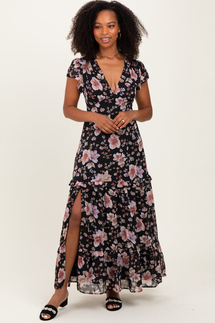 woman wearing a black floral maxi dress with ruffle details and a thigh-high slit